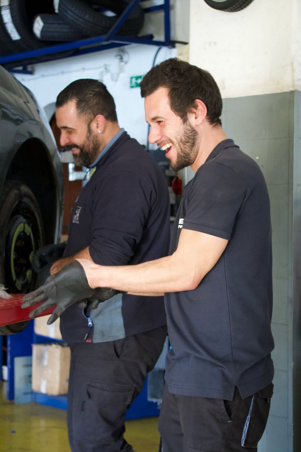 Equipa da Soprocar a trabalhar na oficina, a sorrir junto a um pneu